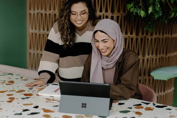 Women laughing while working at laptop